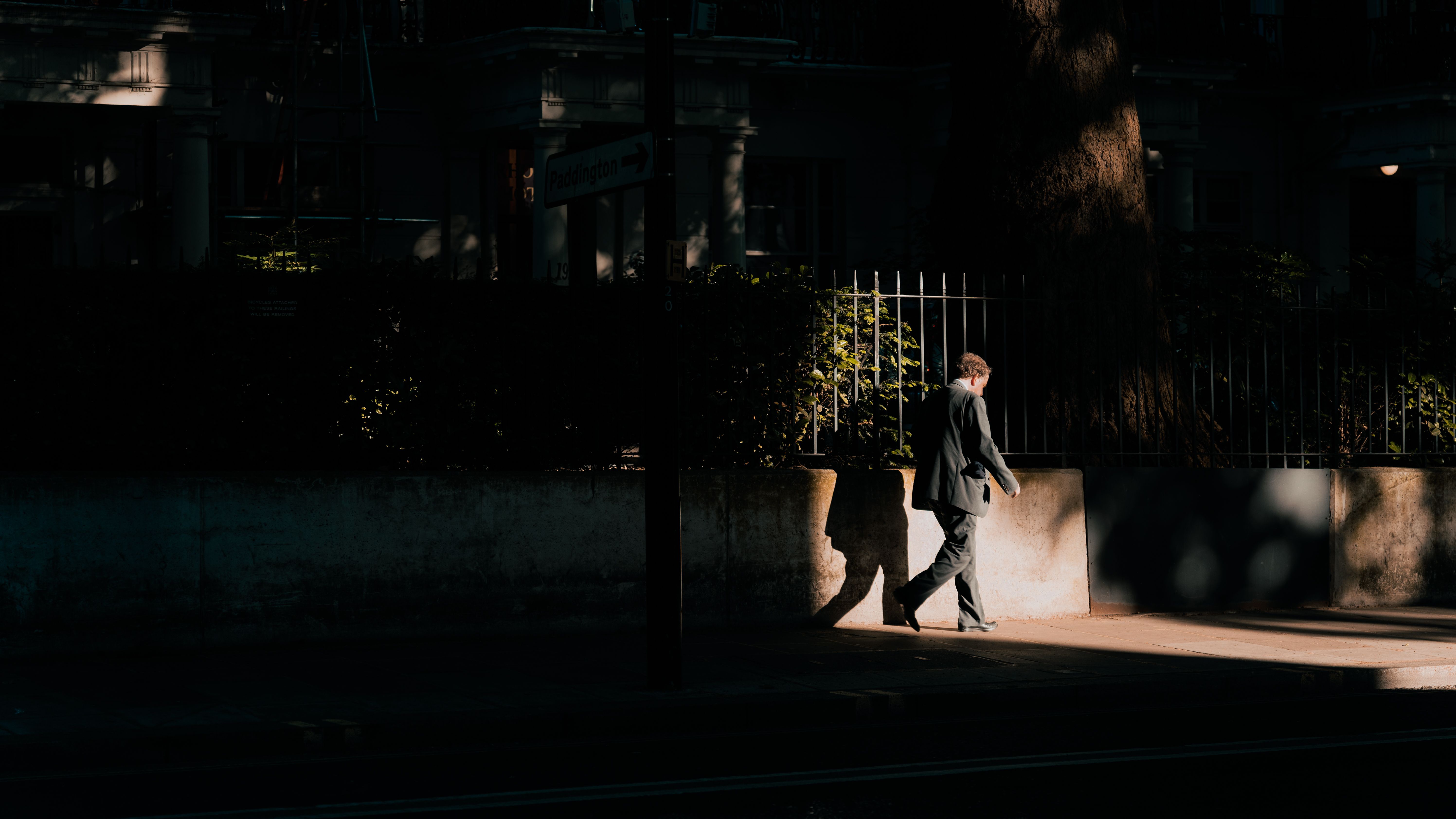 A man walking alone on an empty city sidewalk at dusk